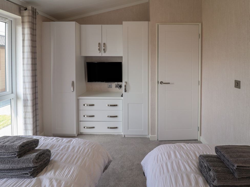 A bedroom with a bed and storage unit at Lodge 1 in Norwich