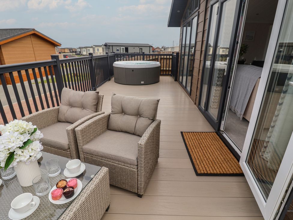 An outdoor deck with seating and a hot tub at Lodge 1 Norwich