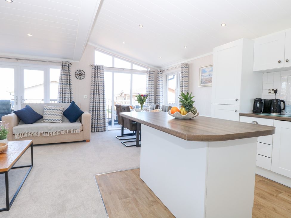 A living room with a sofa and dining table at Sandy Snug in Bacton