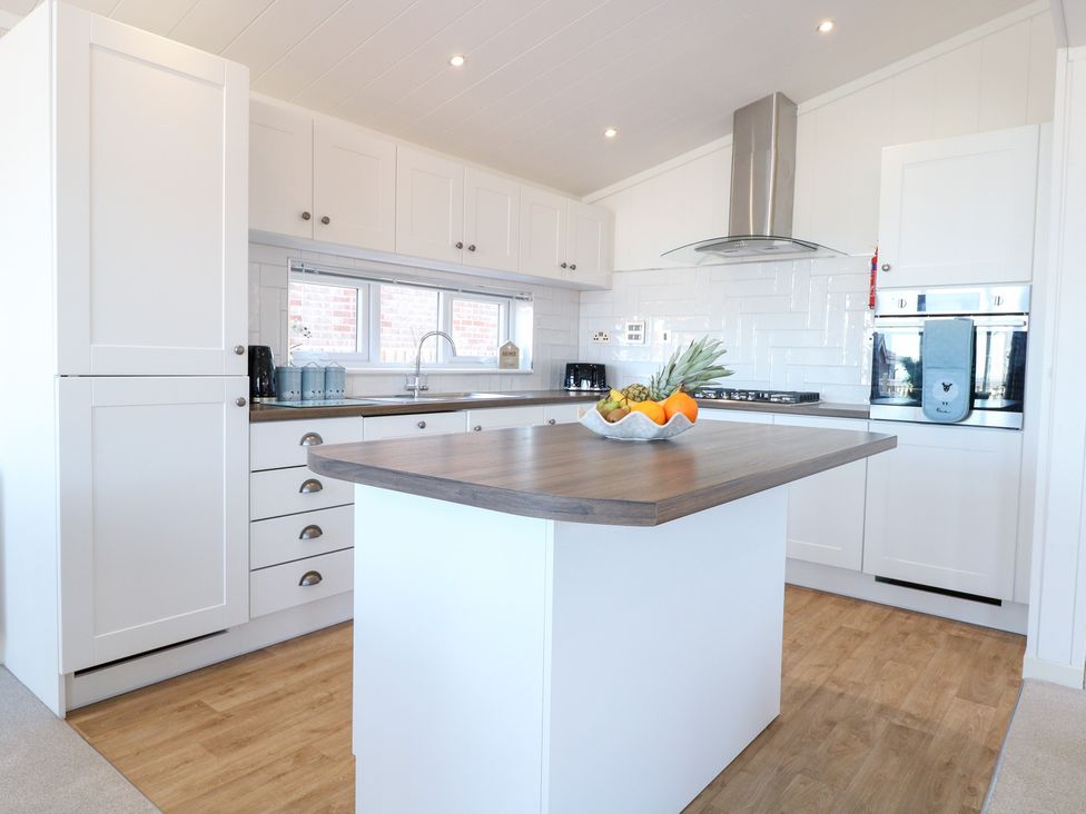 A kitchen with an island and appliances at Sandy Snug in Bacton
