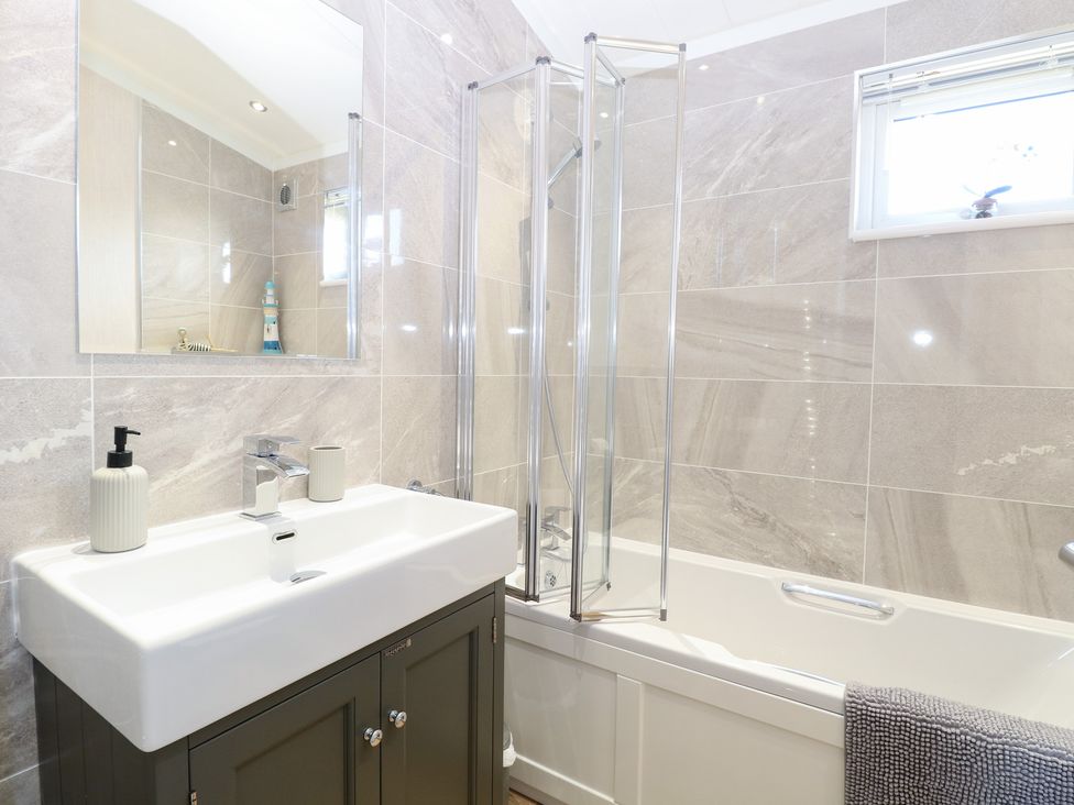 A bathroom with a sink and bathtub at Sandy Snug in Bacton