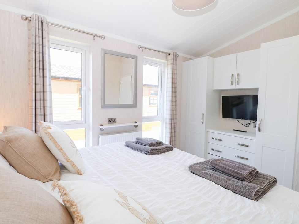 A bedroom with a bed and a television at Sandy Snug in Bacton