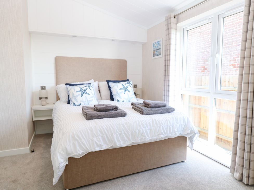 A bedroom with a bed and bedside table at Sandy Snug in Bacton