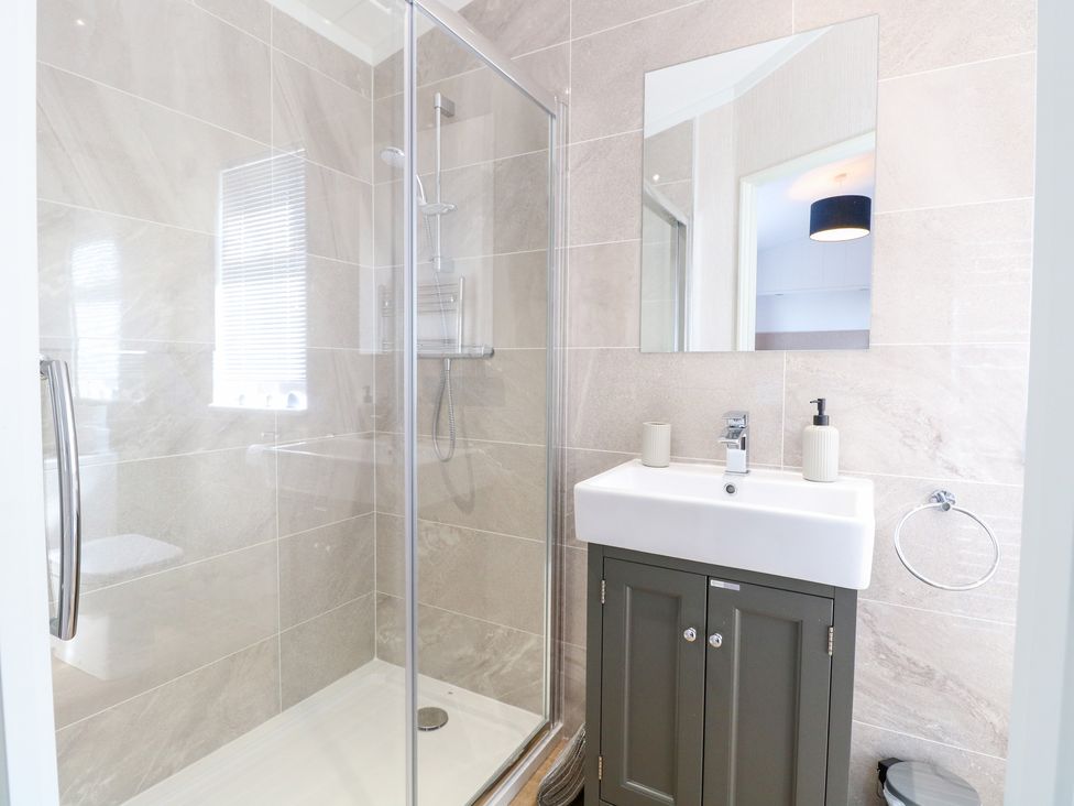 A bathroom with a shower and sink at Sandy Snug in Bacton