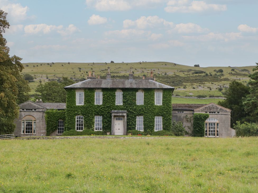 A house with greenery on the facade and surrounding landscape at Huntsman's Cottage in Cartmel