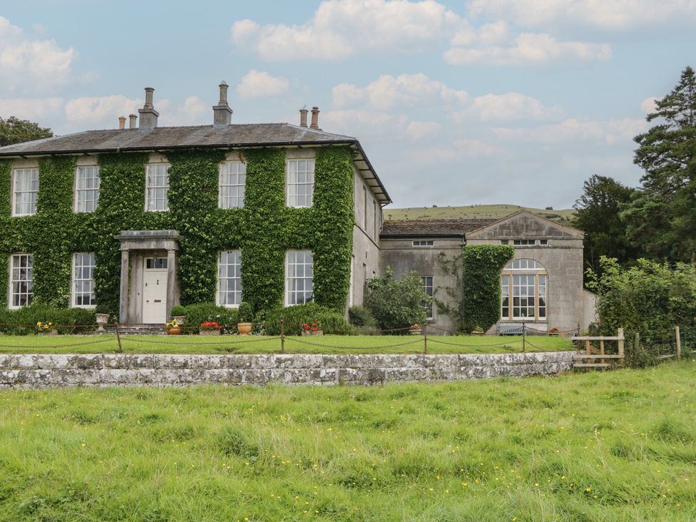 A house with ivy and a garden at Huntsman's Cottage in Cartmel