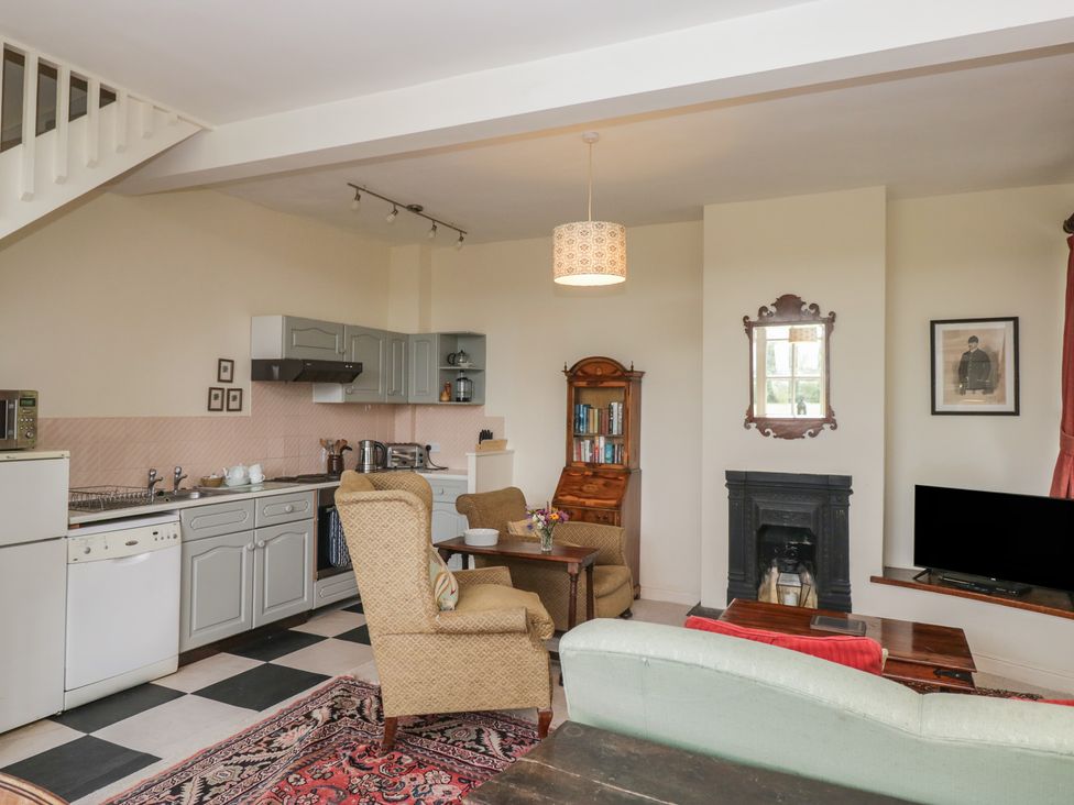 A living room with a kitchen area and furniture at Huntsman's Cottage in Cartmel