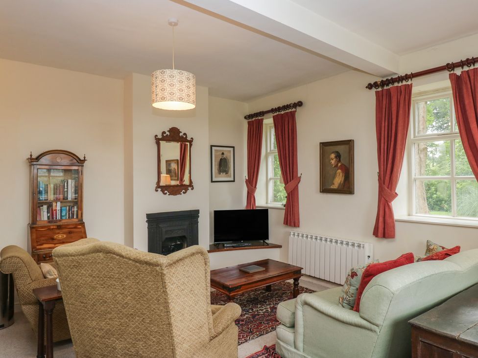 A living room with a sofa, armchairs and a television at Huntsman's Cottage in Cartmel