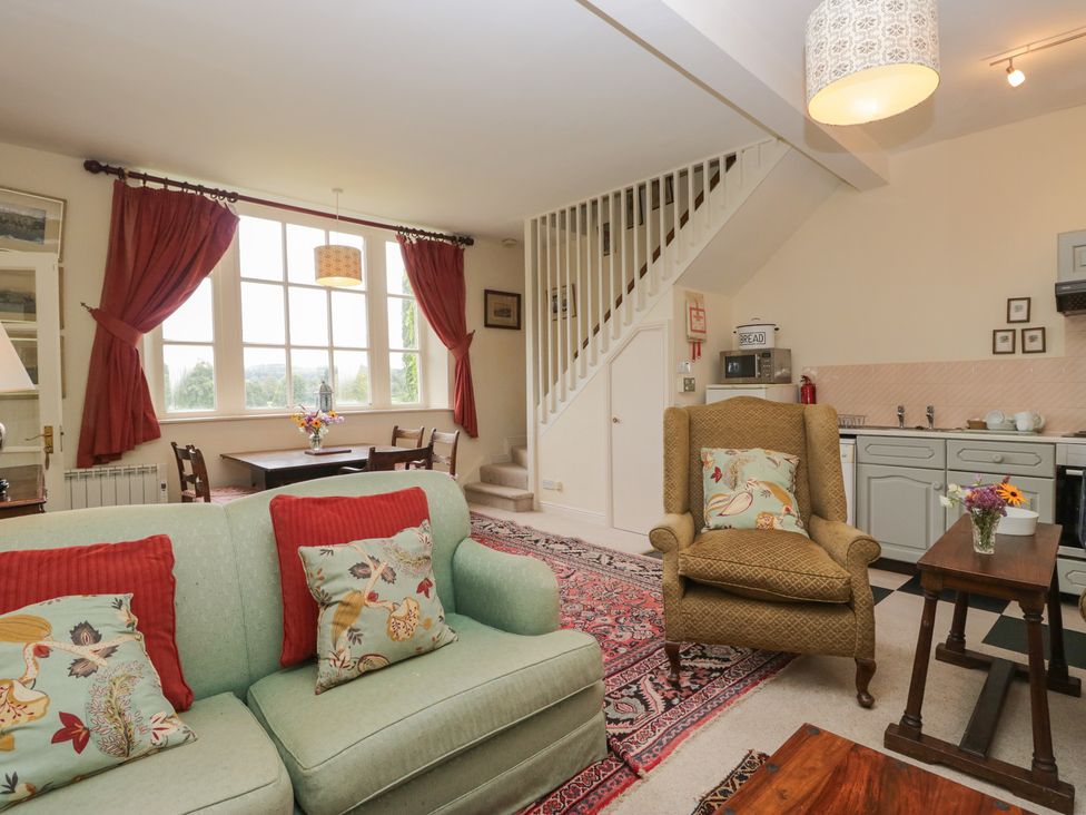 A living room with a sofa and a dining table at Huntsman's Cottage in Cartmel