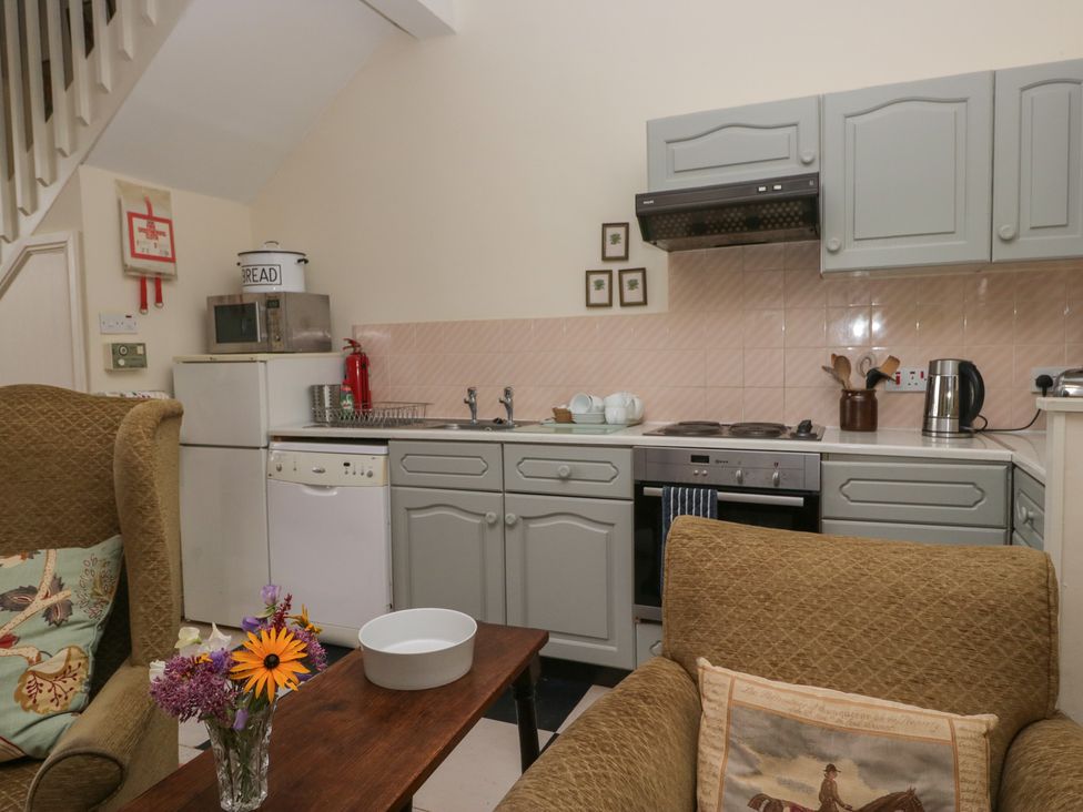 A kitchen with appliances and furniture at Huntsman's Cottage in Cartmel