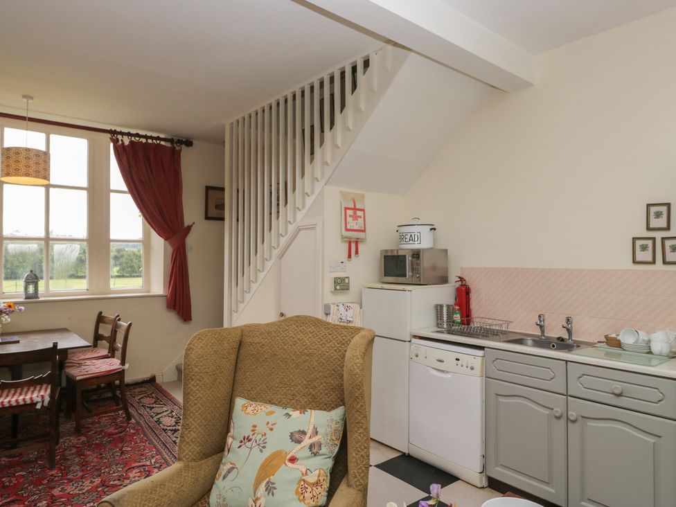 A kitchen with dining area and staircase at Huntsman's Cottage in Cartmel