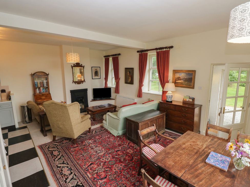 A living room with a sofa, a coffee table, and a dining table at Huntsman's Cottage in Cartmel
