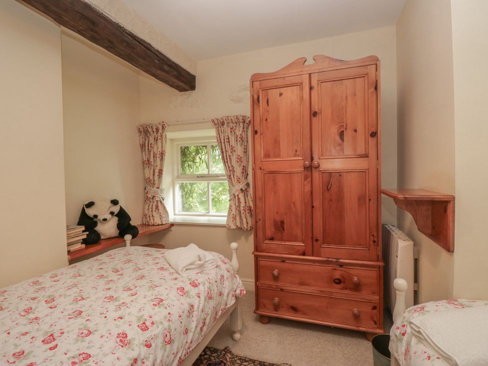 A bedroom with a bed and wardrobe at Huntsman's Cottage in Cartmel