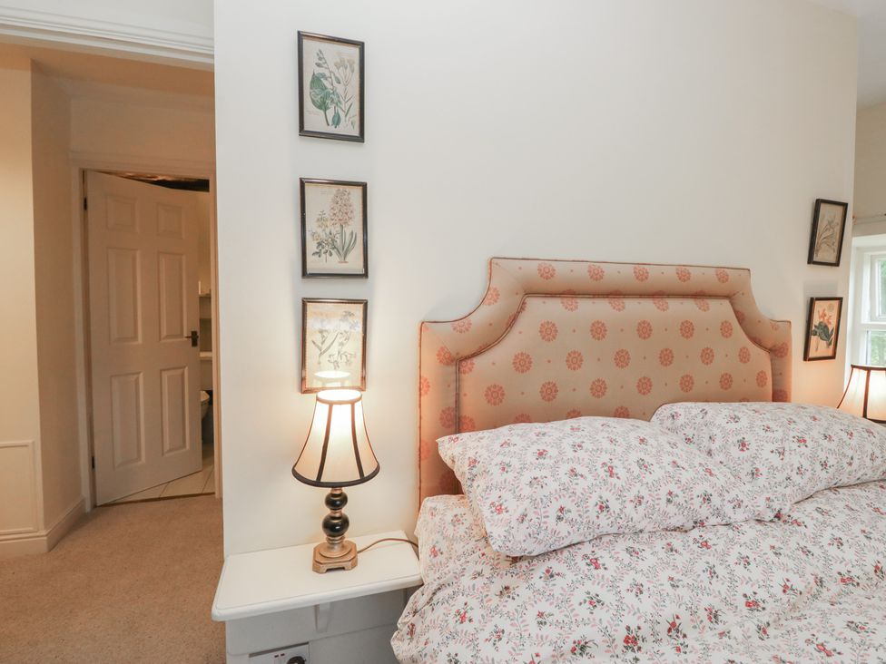 A bedroom with a bed and bedside lamp at Huntsman's Cottage in Cartmel