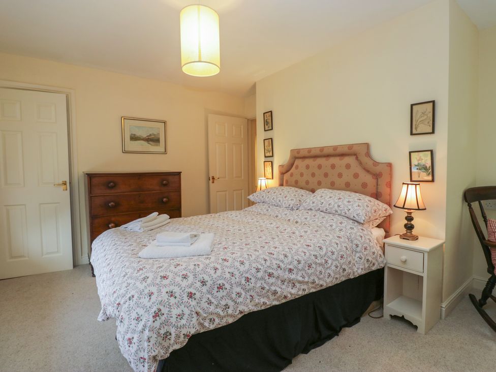 A bedroom with a bed and nightstands at Huntsman's Cottage in Cartmel