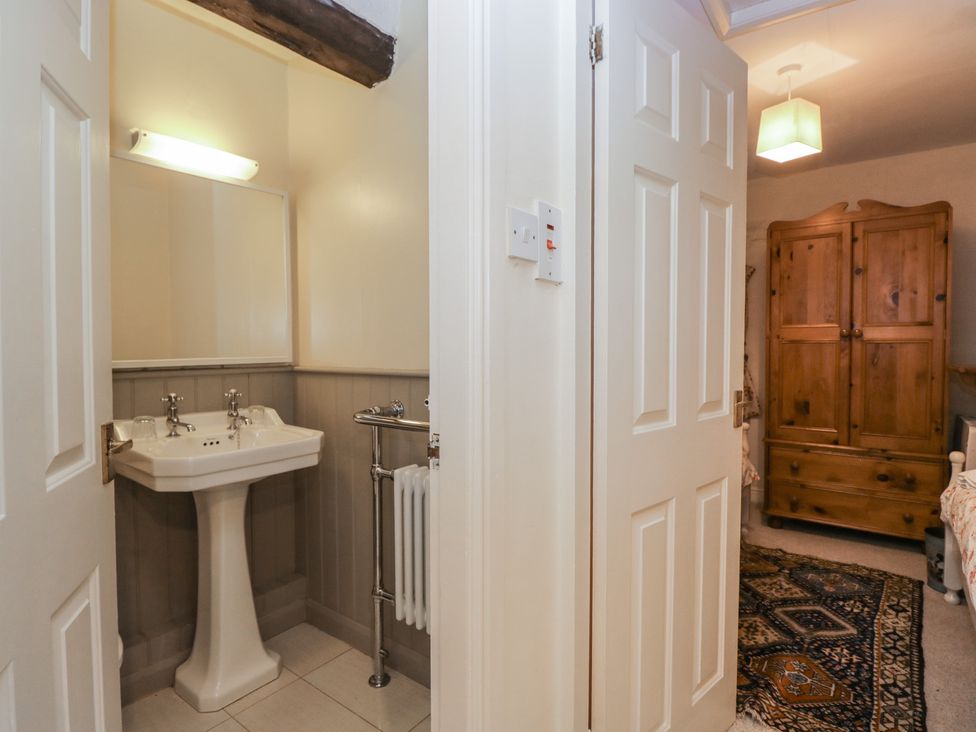 A bathroom with a sink and mirror at Huntsman's Cottage in Cartmel