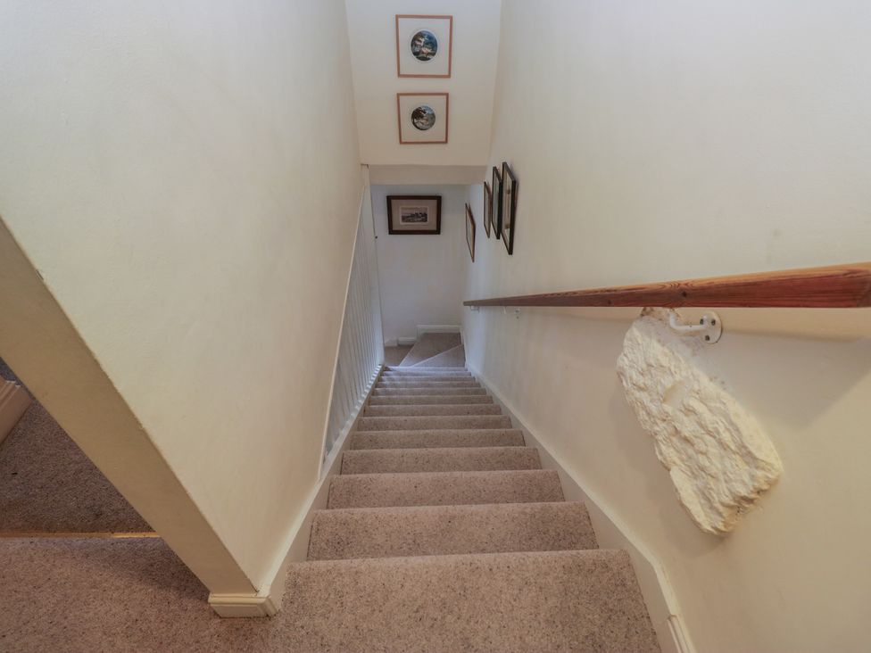 A staircase with pictures on the wall at Huntsman's Cottage in Cartmel
