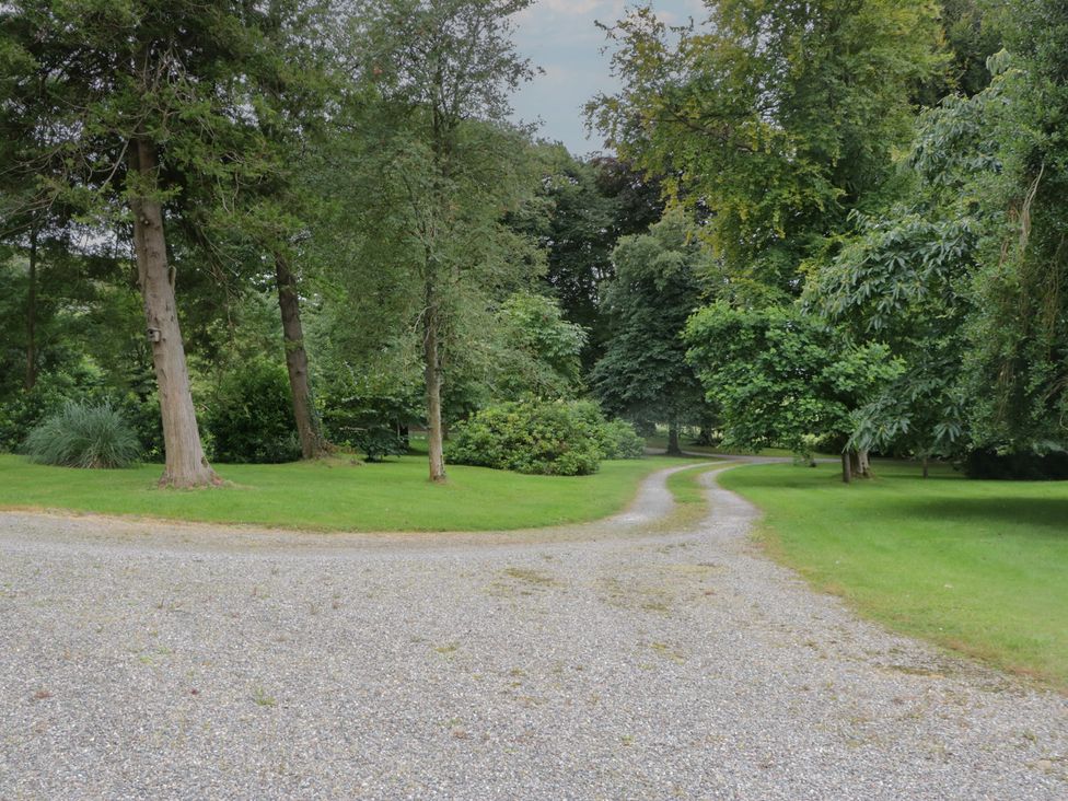 A gravel path leading through trees in a garden at Huntsman's Cottage in Cartmel
