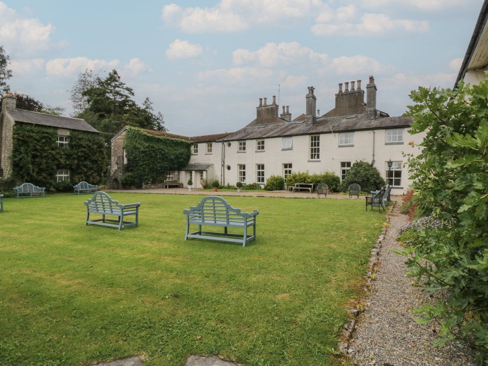 A garden with benches and pathways at The Laundrymaid's Cottage in Cartmel