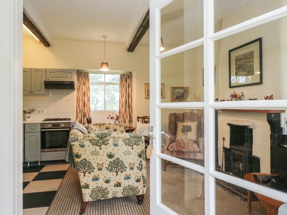 A kitchen with a view of the living area at The Laundrymaid's Cottage in Cartmel