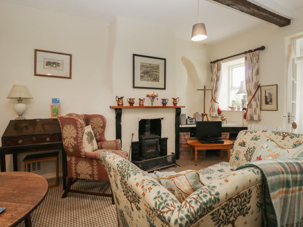 A living room with furniture and a fireplace at The Laundrymaid's Cottage in Cartmel