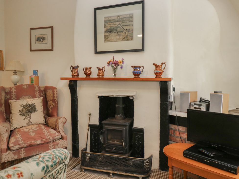 A living room with a fireplace and a sofa at The Laundrymaid's Cottage in Cartmel