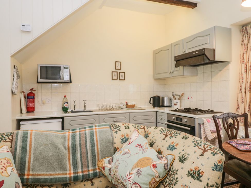 A kitchen with microwave, stove and sink at The Laundrymaid's Cottage in Cartmel