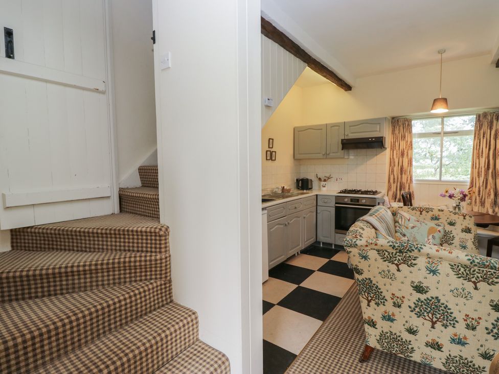 A kitchen area with a staircase and a sofa at The Laundrymaid's Cottage in Cartmel