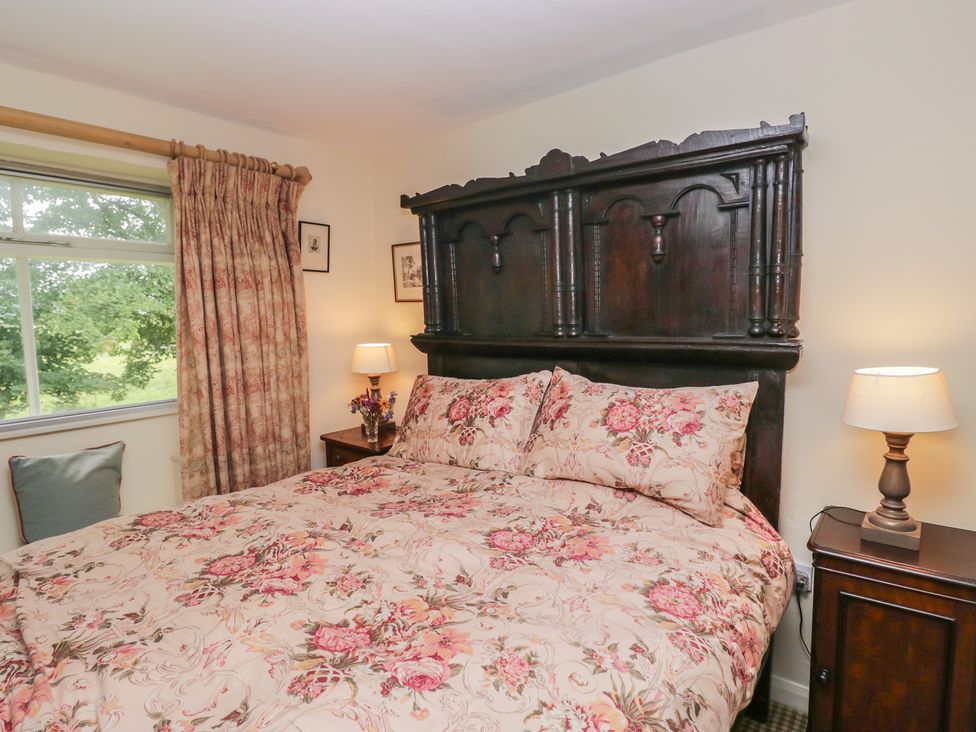 A bedroom with a bed and nightstand at The Laundrymaid's Cottage in Cartmel