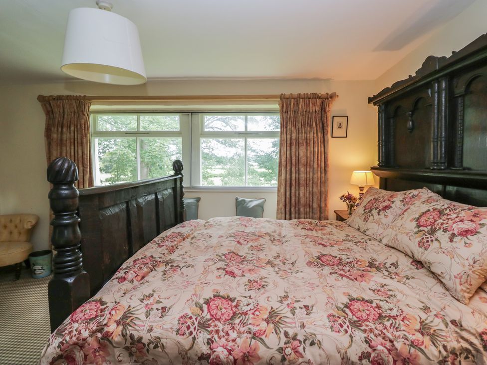 A bedroom with a large bed and window at The Laundrymaid's Cottage in Cartmel
