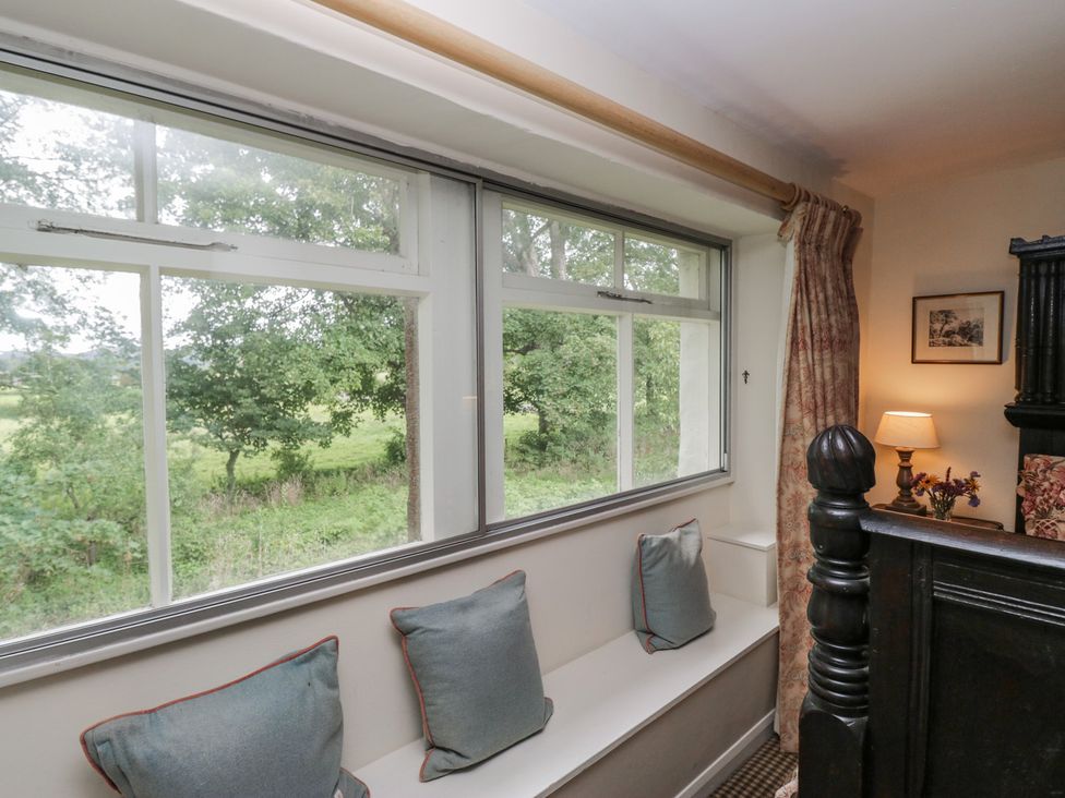 A bedroom with a window and seating area at The Laundrymaid's Cottage in Cartmel