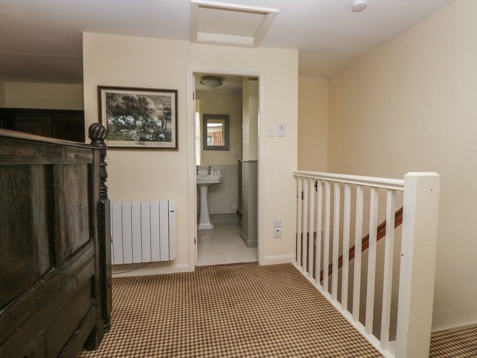 A hallway with stairs and a sink at The Laundrymaid's Cottage in Cartmel