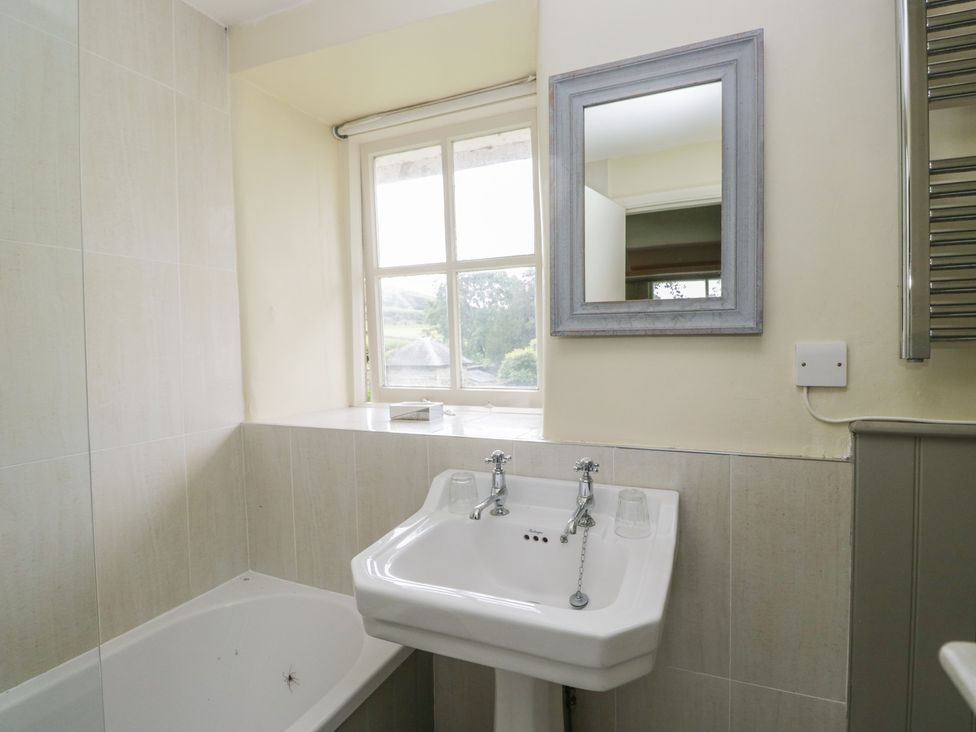 A bathroom with a bathtub and sink at The Laundrymaid's Cottage in Cartmel