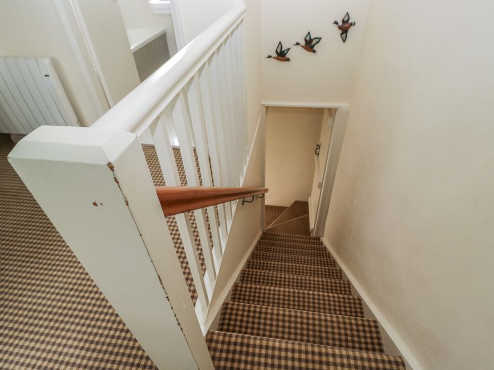 A staircase with a banister and decorative birds at The Laundrymaid's Cottage in Cartmel