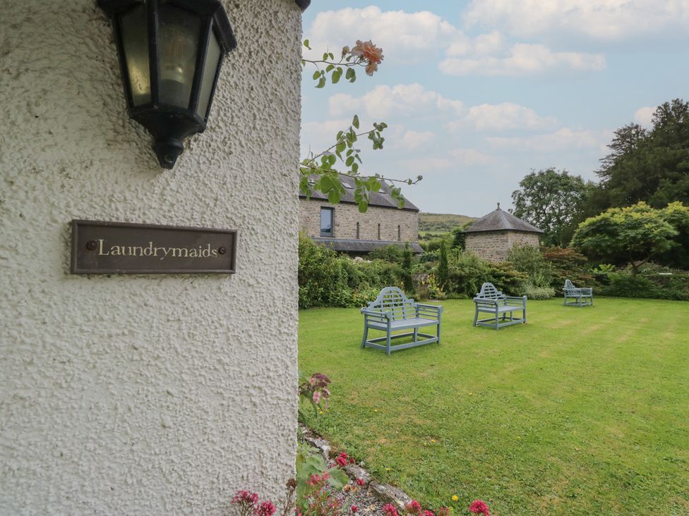 A garden with benches and a sign at The Laundrymaid's Cottage in Cartmel