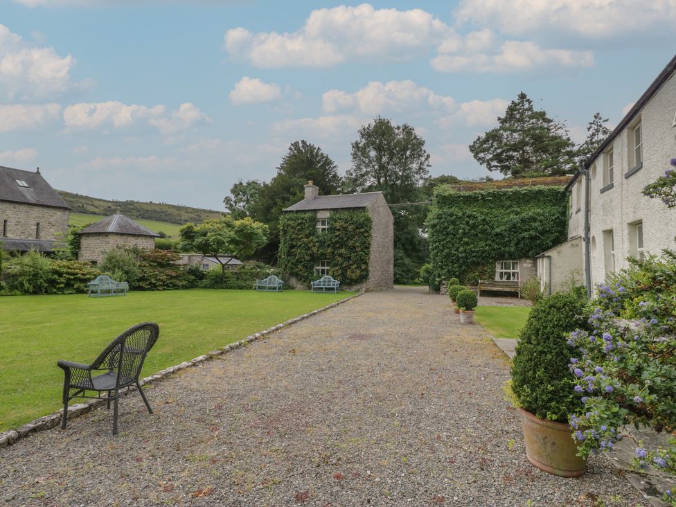 A garden with buildings and seating areas at The Laundrymaid's Cottage in Cartmel