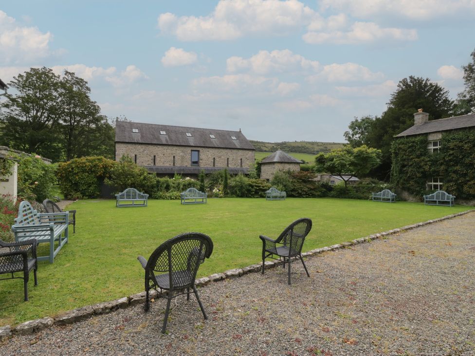 A garden with chairs and a building at The Laundrymaid's Cottage in Cartmel