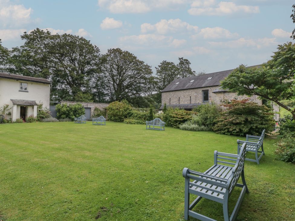 A garden with benches and grass at The Laundrymaid's Cottage in Cartmel