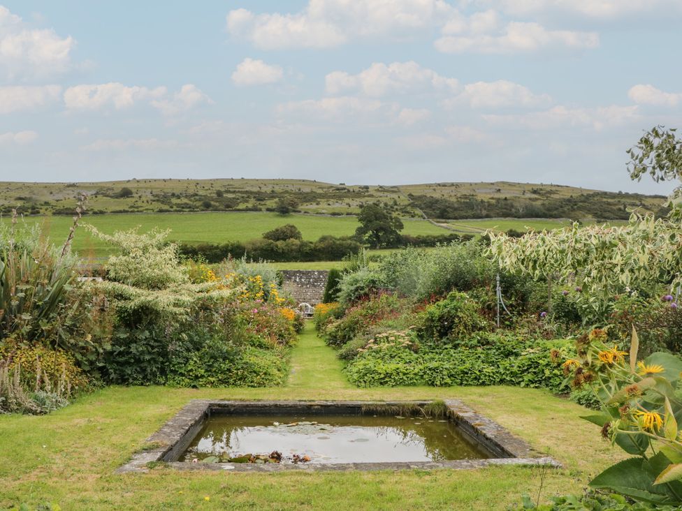 A garden with a pond and plants at The Laundrymaid's Cottage in Cartmel