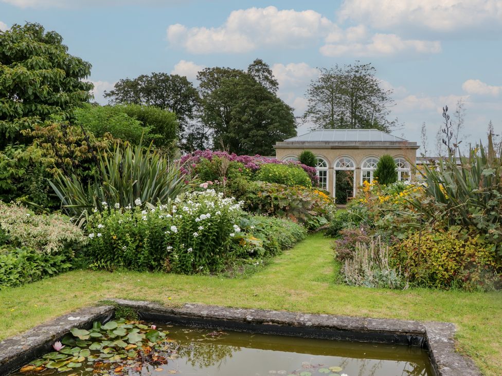 A garden with a pond and flowers at The Laundrymaid's Cottage in Cartmel