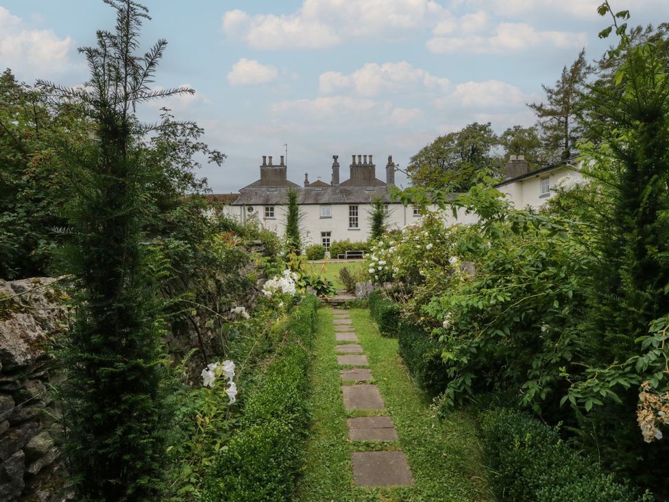 A garden with a pathway and house background at The Laundrymaid's Cottage in Cartmel