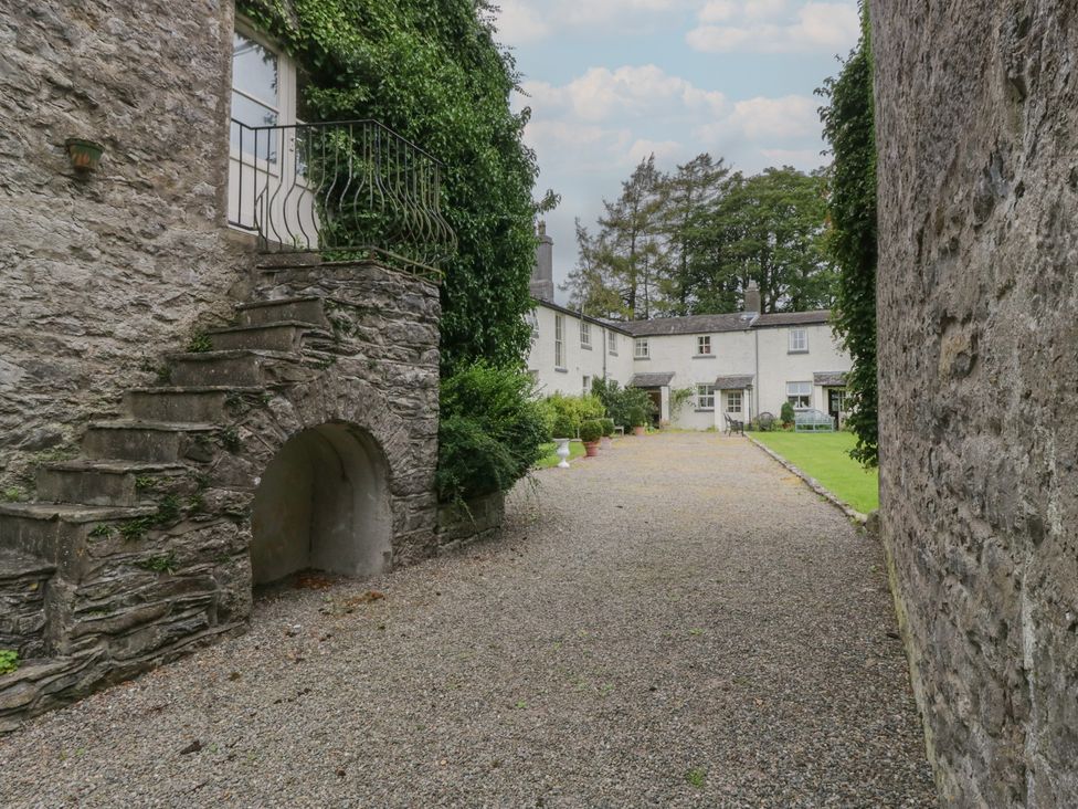 An outdoor courtyard with gravel path and surrounding stone walls at The Laundrymaid's Cottage in Cartmel