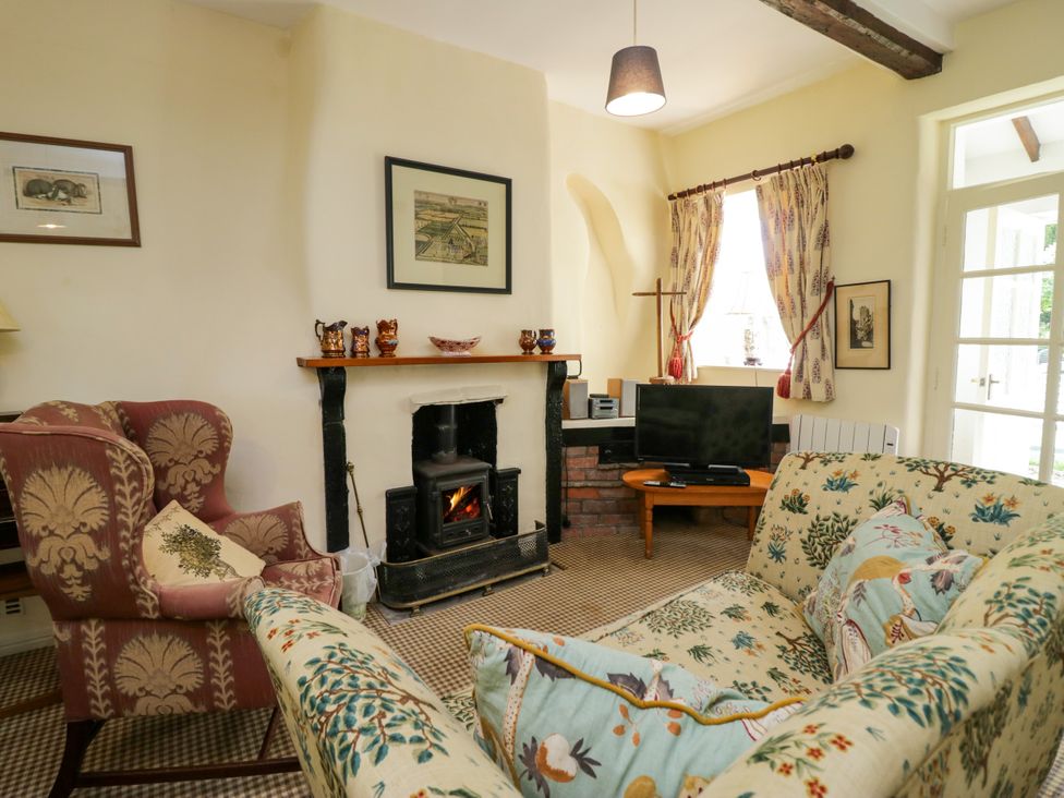 A living room with a fireplace and a sofa at The Laundrymaid's Cottage in Cartmel