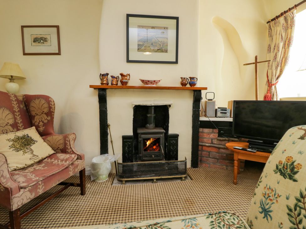 A living room with a fireplace and television at The Laundrymaid's Cottage in Cartmel