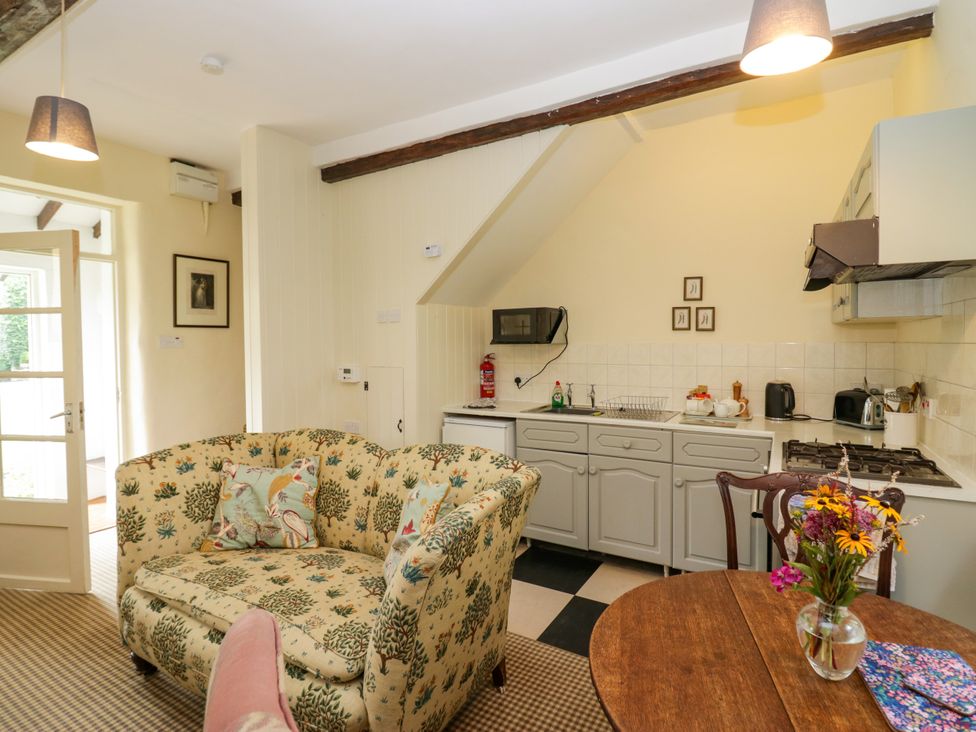 A kitchen with a sofa and dining table at The Laundrymaid's Cottage in Cartmel