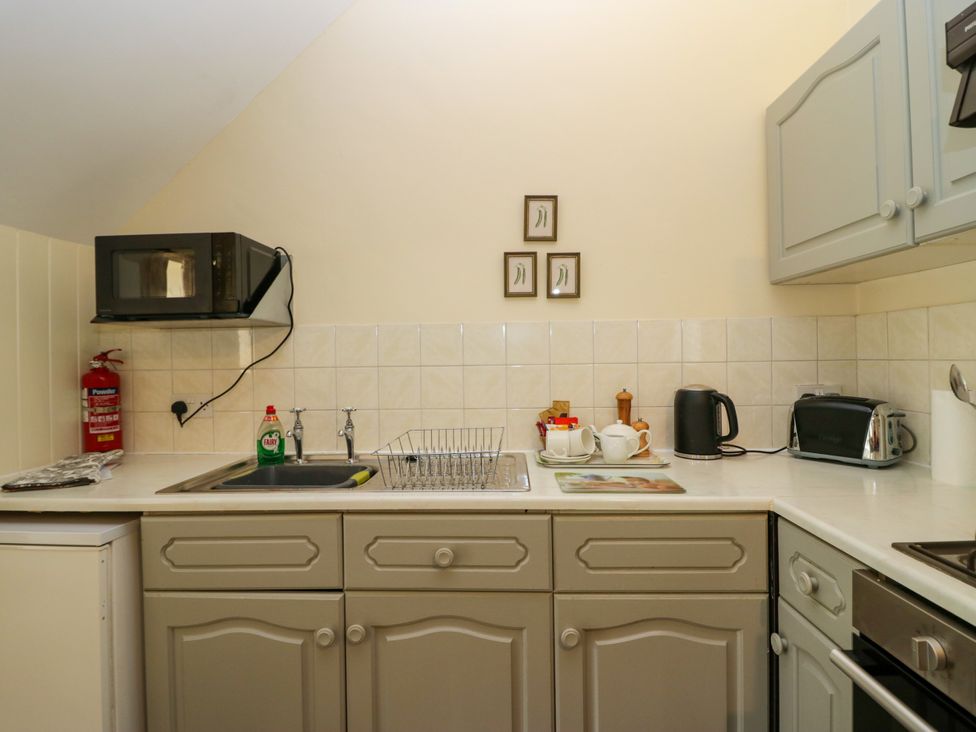 A kitchen with a sink and microwave at The Laundrymaid's Cottage in Cartmel