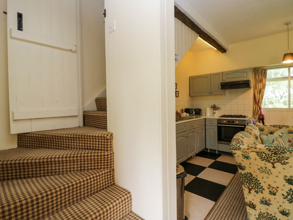 A kitchen with a staircase leading up at The Laundrymaid's Cottage in Cartmel
