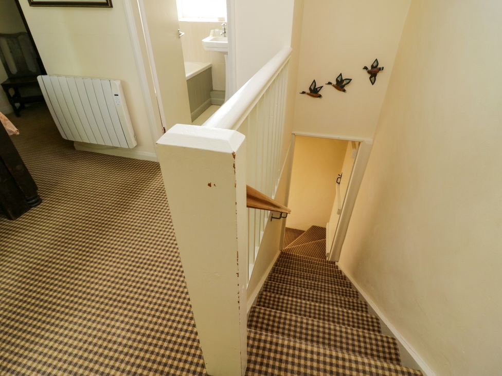 A hallway with stairs and a door at The Laundrymaid's Cottage in Cartmel