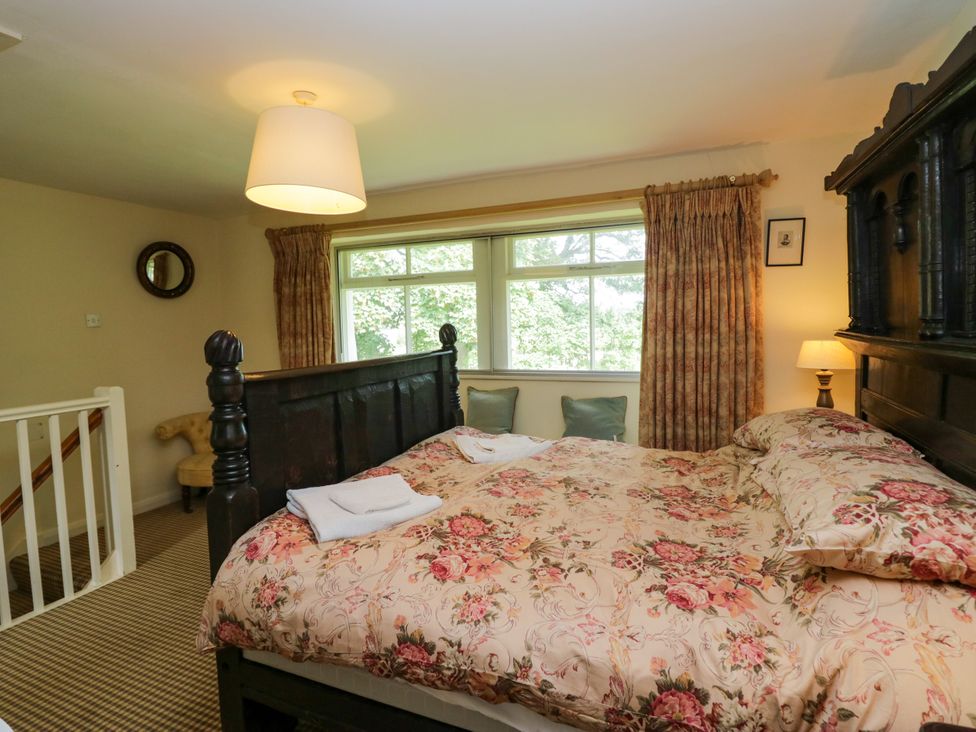 A bedroom with a bed and windows at The Laundrymaid's Cottage in Cartmel