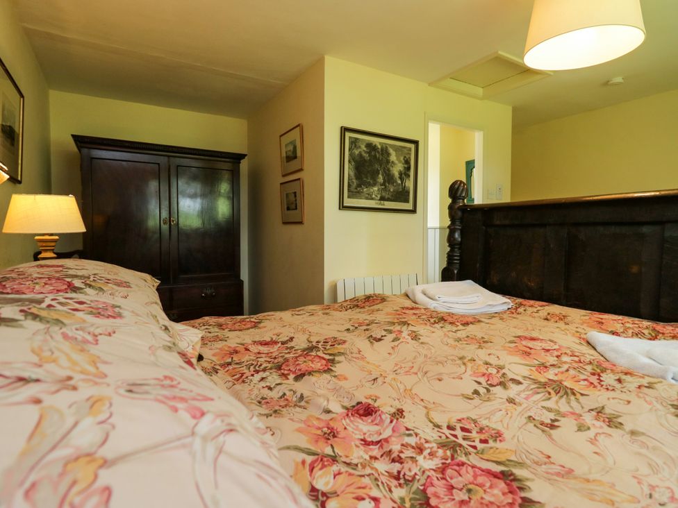A bedroom with a bed and wardrobe at The Laundrymaid's Cottage in Cartmel